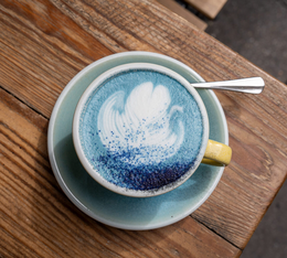 tasse de latte bleu la main noire